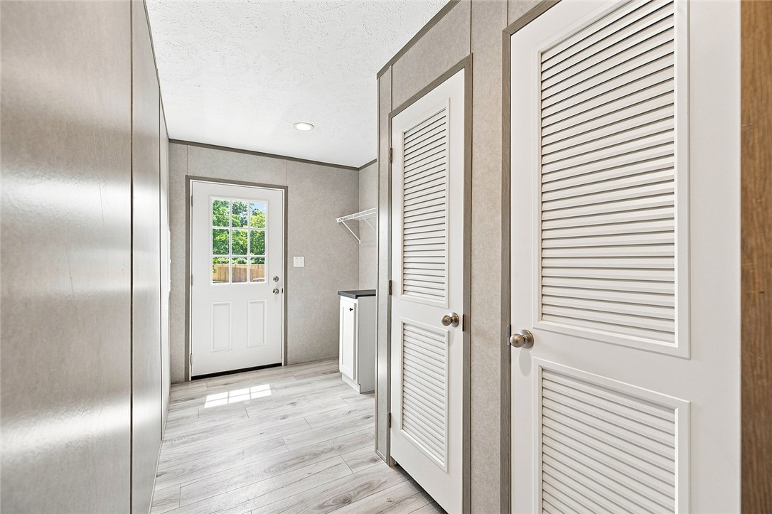 112 Purdy Road Iva, SC 29655 - Photo 17 of 33 Louvered doors line a functional transitional hallway leading toward an exterior door.