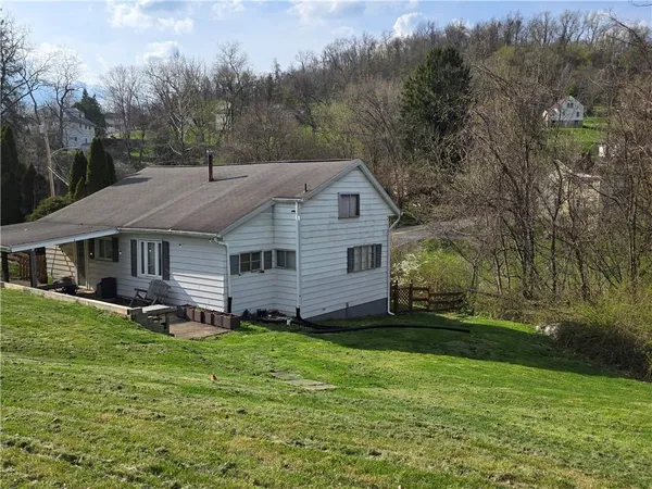 a aerial view of a house next to a big yard and large trees