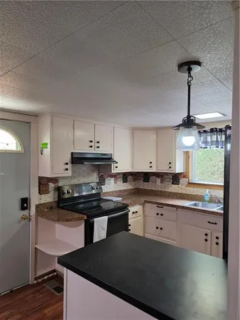 a kitchen with granite countertop a sink a counter space appliances and cabinets