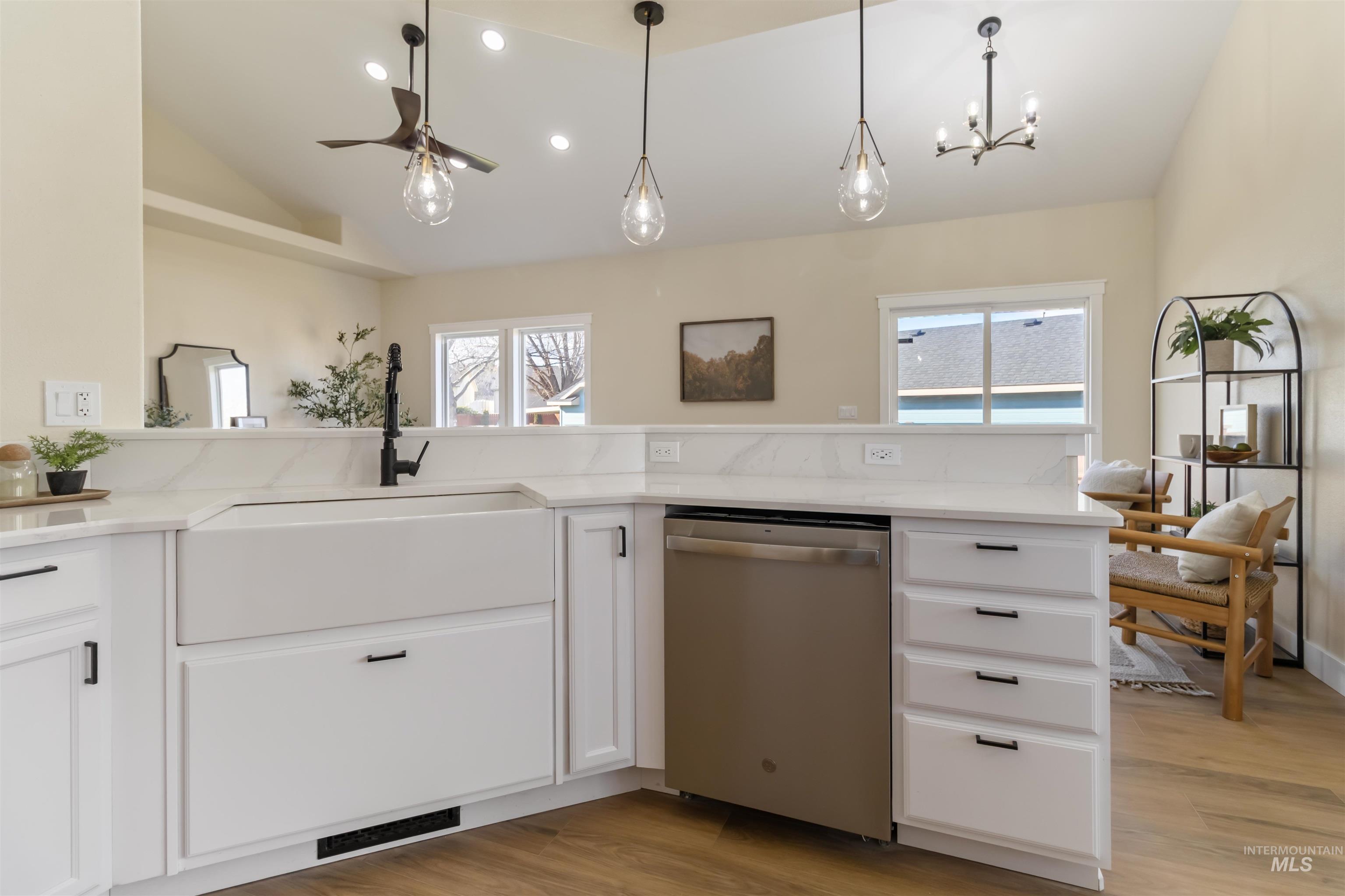 3201 Raintree Drive Nampa, ID 83686 - Photo 24 of 50 Kitchen with vaulted ceiling, stainless steel dishwasher, white cabinets, light stone countertops, and light wood-style floors