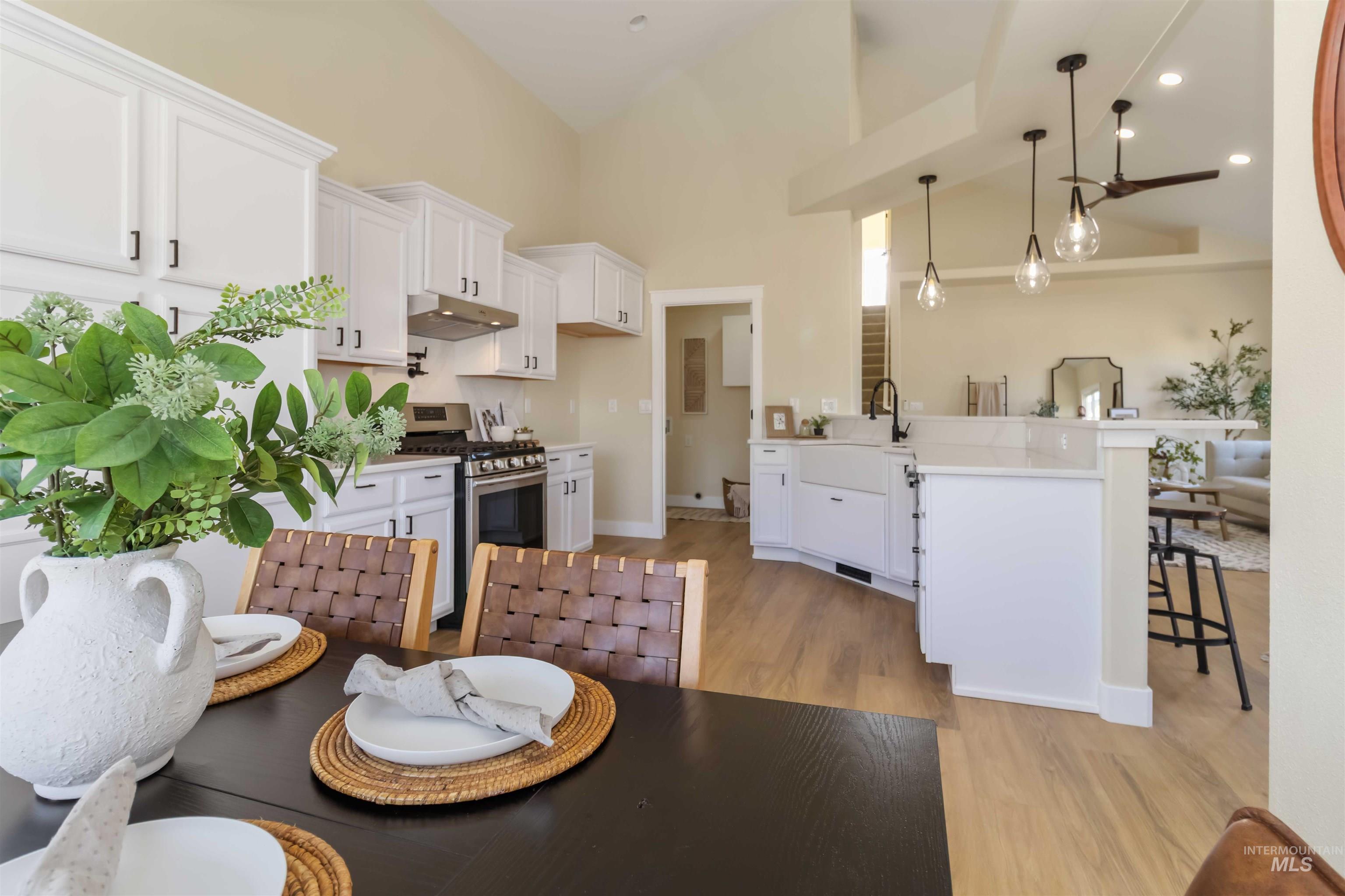 3201 Raintree Drive Nampa, ID 83686 - Photo 25 of 50 Kitchen featuring stainless steel gas range oven, white cabinets, high vaulted ceiling, a breakfast bar, and a peninsula