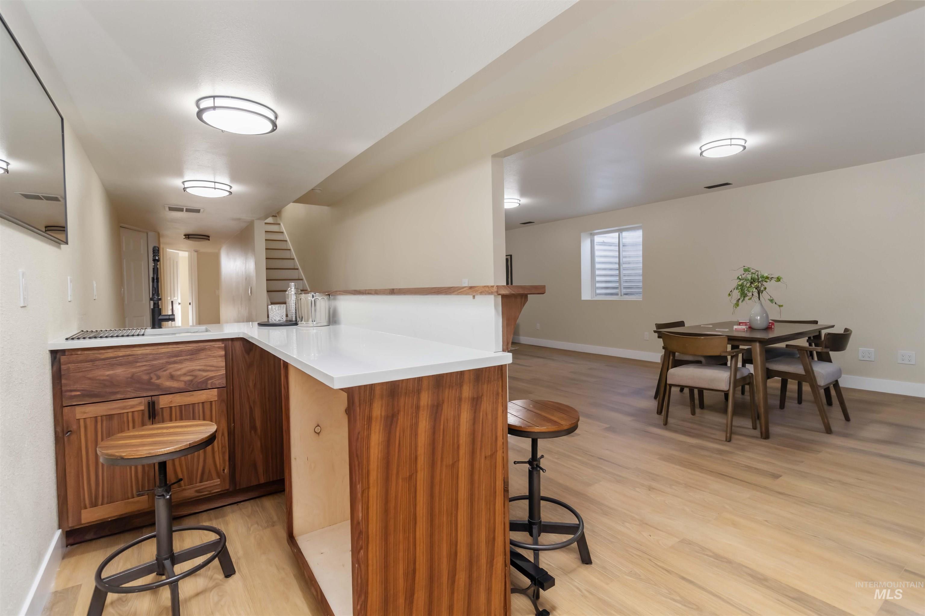 3201 Raintree Drive Nampa, ID 83686 - Photo 37 of 50 Bar with stairs, light wood-type flooring, and brown cabinetry