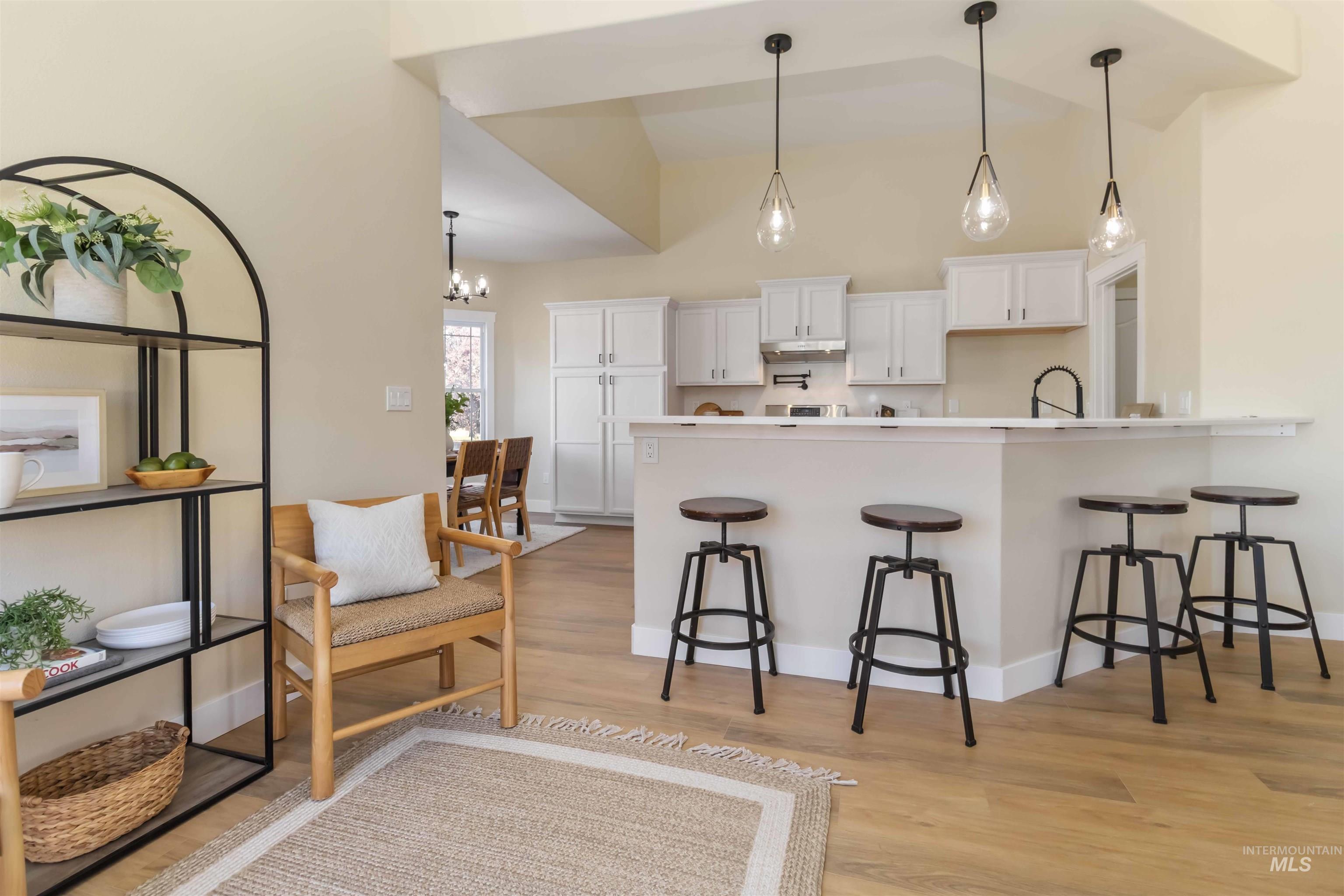 3201 Raintree Drive Nampa, ID 83686 - Photo 10 of 50 Kitchen featuring a peninsula, white cabinetry, pendant lighting, a breakfast bar area, and high vaulted ceiling