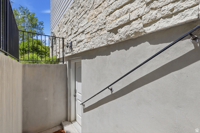 10676 Urban Rdg Cove South Jordan, UT 84095 - Photo 41 of 48 Lower-level entry featuring a paneled door, exterior wall lantern, and a wrought iron handrail