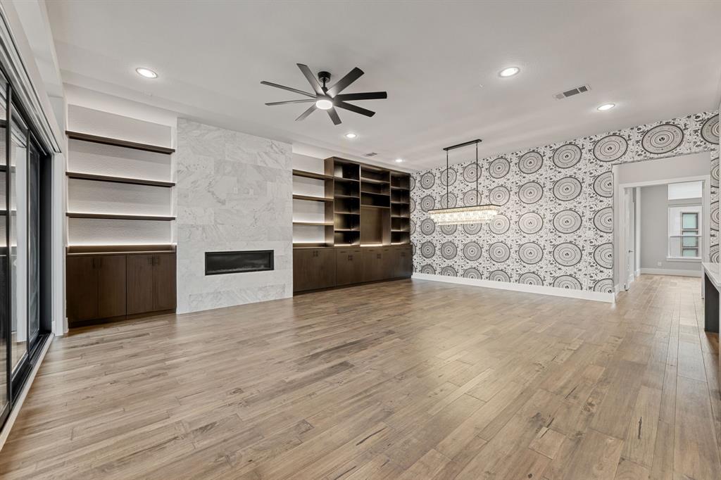 7854 Element Avenue Plano, TX 75024 - Photo 2 of 38 Unfurnished living room with a fireplace, light wood-type flooring, ceiling fan, recessed lighting, Versace wallpaper, and built in shelves