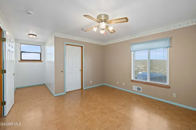 a view of an empty room with window and wooden floor