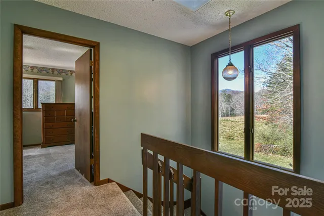 a view of a hallway with wooden floor and a bathroom