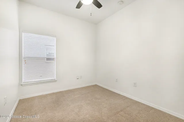 an empty room with a window and a ceiling fan