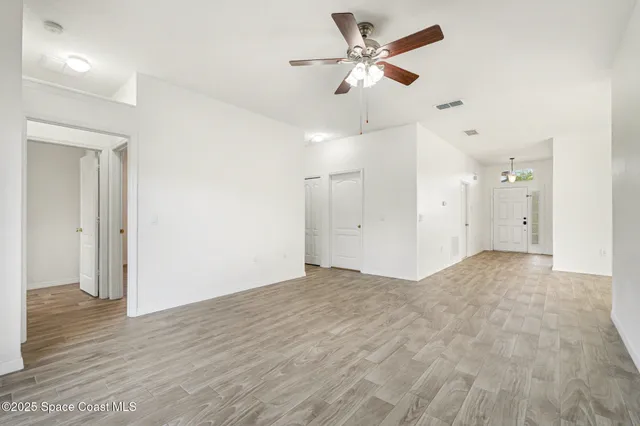 a view of a big room with wooden floor and a ceiling fan