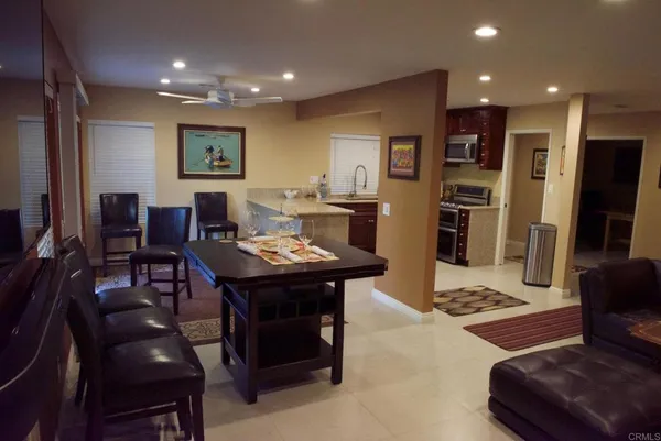 a living room with stainless steel appliances furniture a rug and a flat screen tv