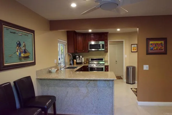 a kitchen with stainless steel appliances granite countertop a refrigerator a sink a stove a dining table and chairs with wooden floor