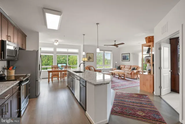 a kitchen with counter top space a sink appliances and living room view