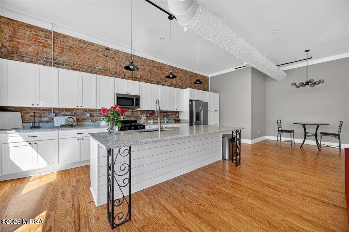 565 Poplar Street Macon, GA 31201 - Photo 4 of 12 a kitchen with stainless steel appliances granite countertop a refrigerator a stove top oven a dining table and chairs with wooden floor