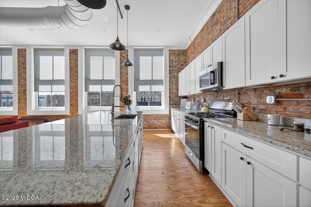 565 Poplar Street Macon, GA 31201 - Photo 7 of 12 a kitchen with stainless steel appliances granite countertop a stove a sink and white cabinets