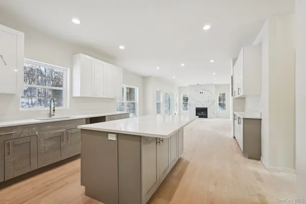 a large white kitchen with a stove a sink a refrigerator and white cabinets with wooden floor