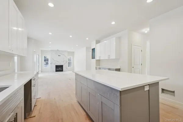 a large white kitchen with kitchen island a sink a stove a refrigerator and white cabinets with wooden floor