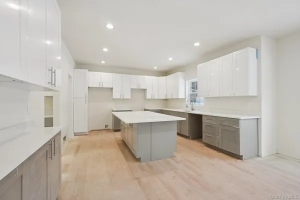 a large kitchen with a large counter top space a sink stainless steel appliances and cabinets