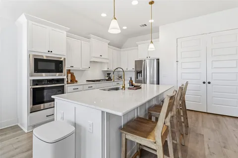 a kitchen with kitchen island a stove a table and chairs in it