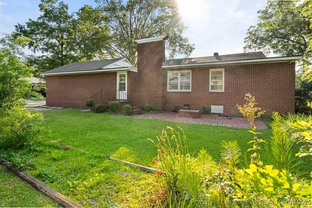 a backyard of a house with table and chairs plants and large tree