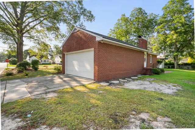 a backyard of a house with plants and large tree