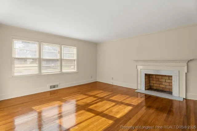 a view of an empty room with a fireplace and a window