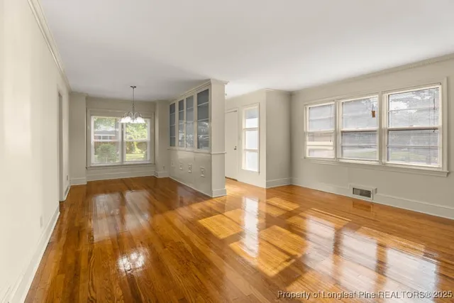 a view of an empty room with a window and wooden floor