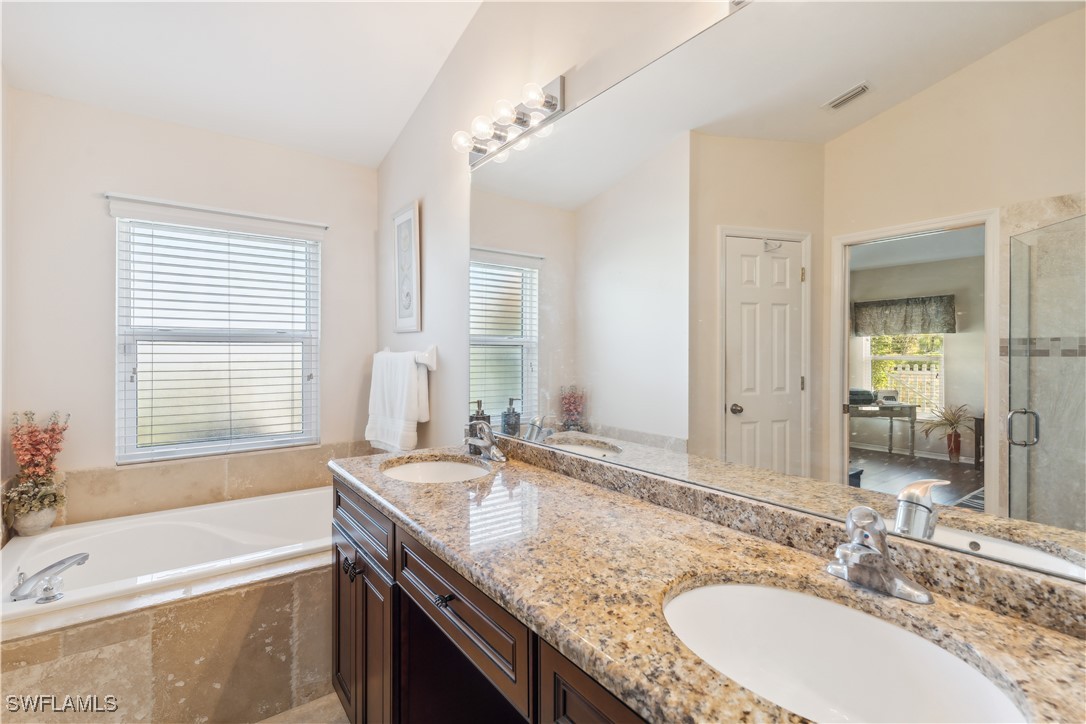 4644 Varsity Circle Lehigh Acres, FL 33971 - Photo 16 of 29 a bathroom with a granite countertop tub sink and mirror