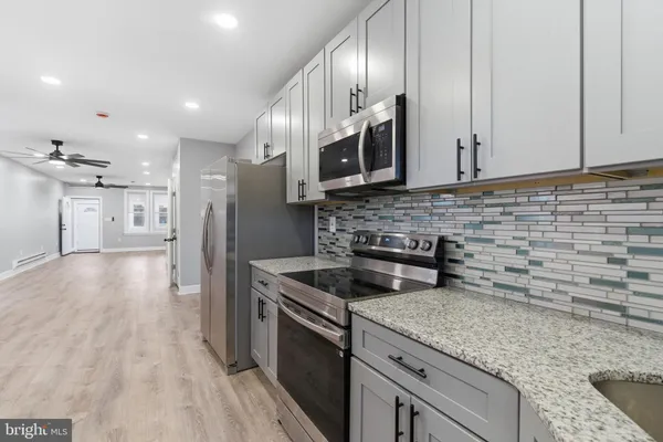a kitchen with stainless steel appliances granite countertop a sink a stove and a wooden floors