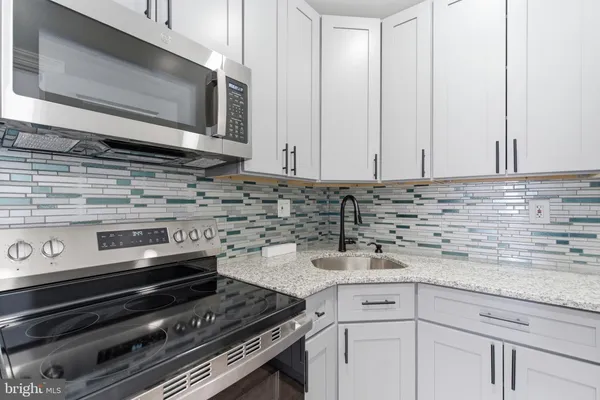 a kitchen with granite countertop a stove microwave and sink