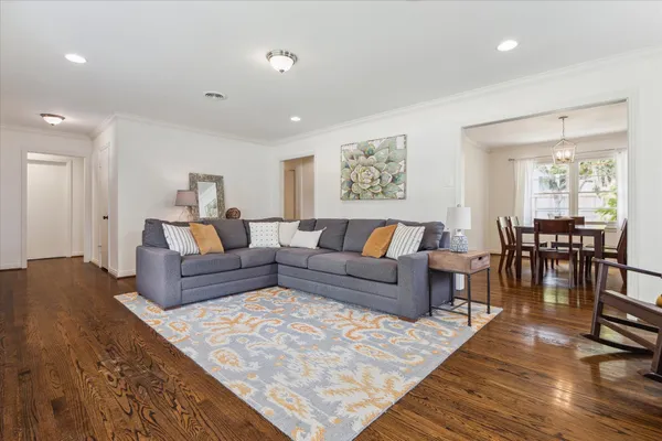 a living room with furniture and a dining table with wooden floor