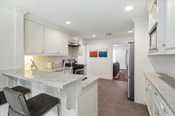 a kitchen with granite countertop white cabinets and refrigerator