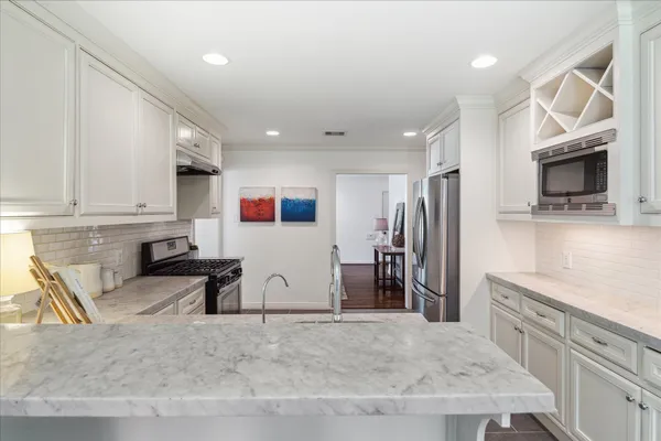 a kitchen with stainless steel appliances kitchen island granite countertop a refrigerator and a sink