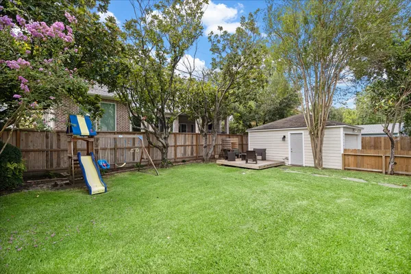 a view of a backyard with a slide and a tree