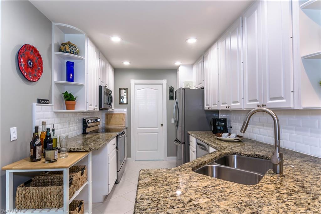 5441 Cove Circle Naples, FL 34119 - Photo 11 of 25 a kitchen with stainless steel appliances granite countertop a sink stove and refrigerator