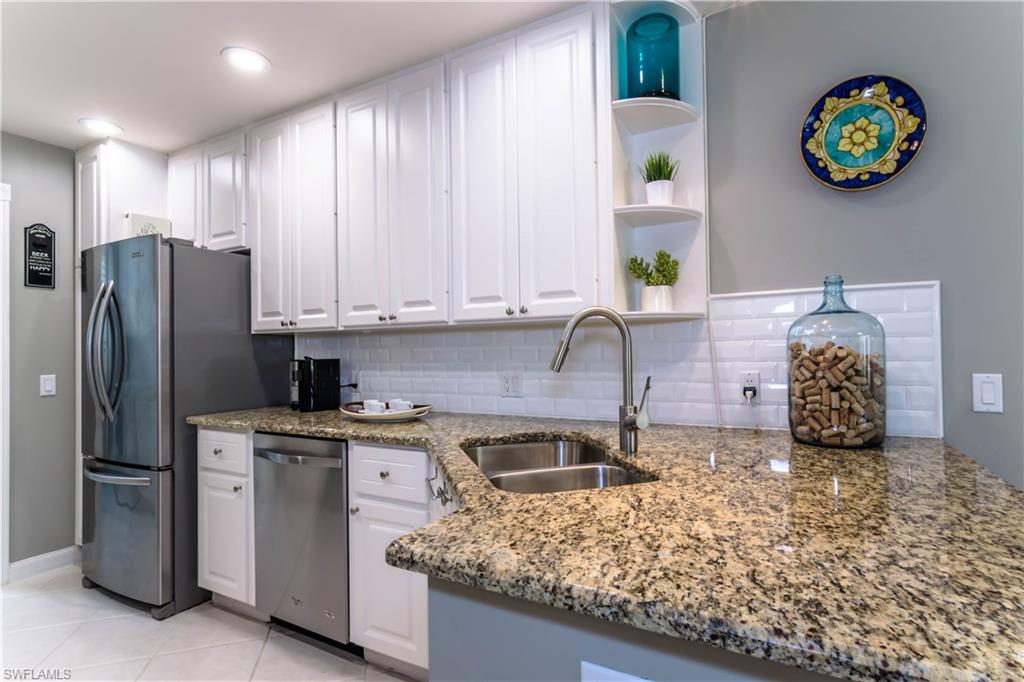 5441 Cove Circle Naples, FL 34119 - Photo 12 of 25 a kitchen with stainless steel appliances granite countertop a sink stove and refrigerator