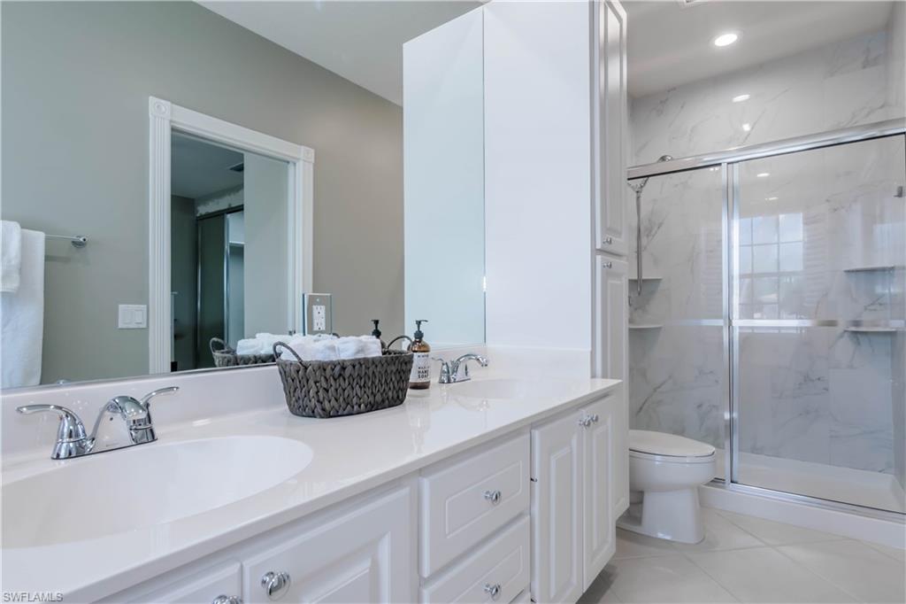 5441 Cove Circle Naples, FL 34119 - Photo 17 of 25 a bathroom with a double vanity sink toilet and shower