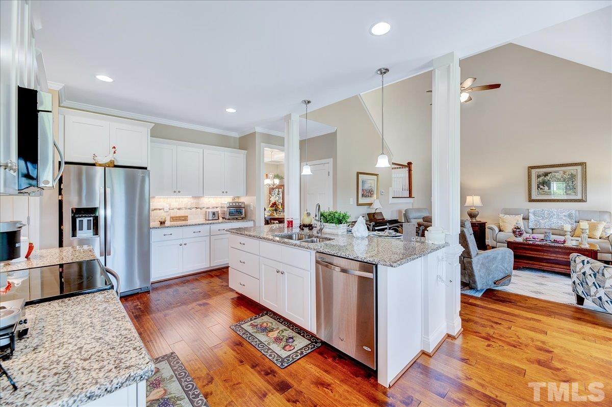 97 Baldwin Ridge Court Willow Spring, NC 27592 - Photo 12 of 46 a kitchen with stainless steel appliances kitchen island granite countertop a refrigerator a stove a sink dishwasher and white cabinets with wooden floor
