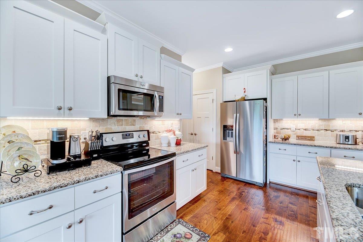 97 Baldwin Ridge Court Willow Spring, NC 27592 - Photo 13 of 46 a kitchen with granite countertop white cabinets and stainless steel appliances