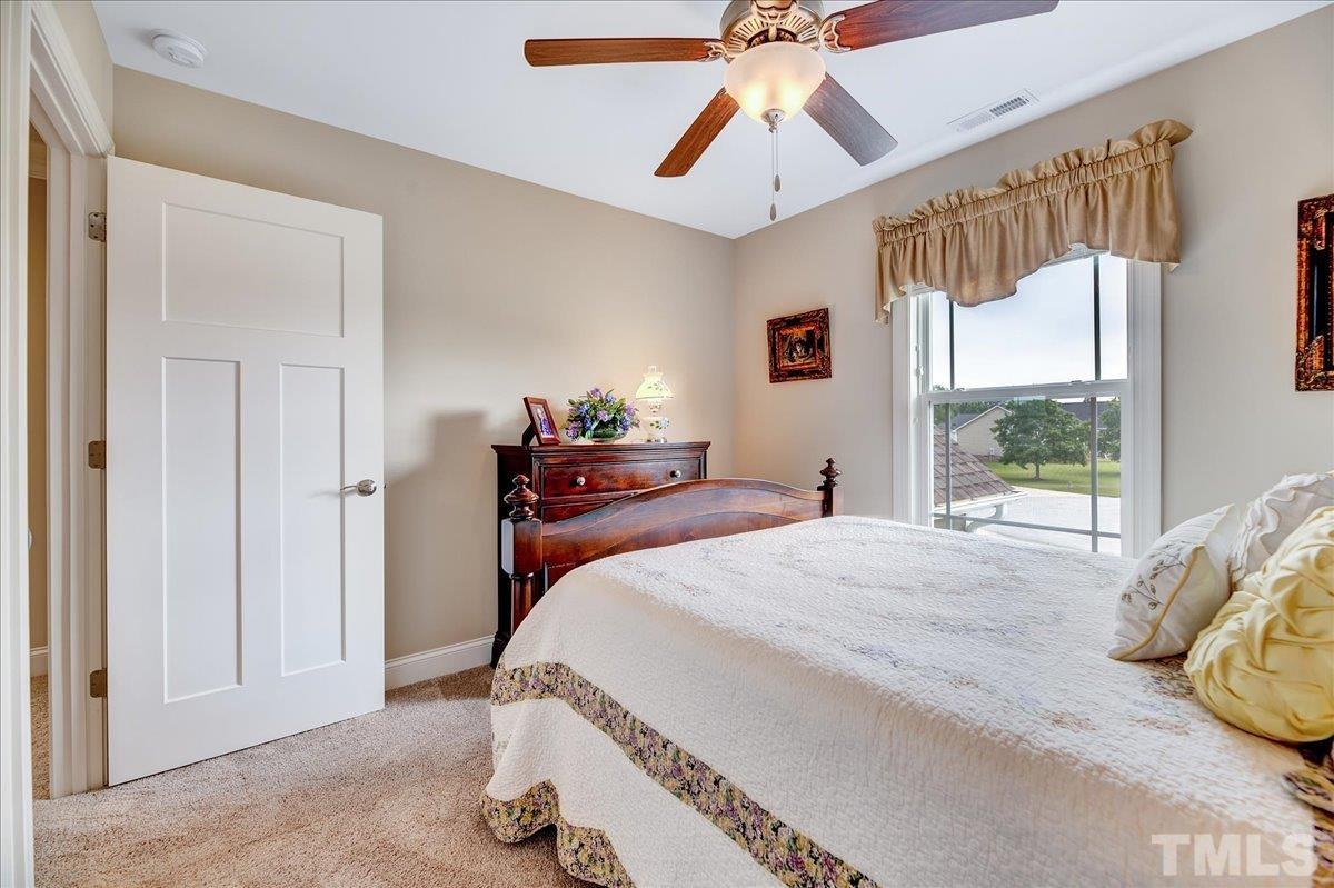 97 Baldwin Ridge Court Willow Spring, NC 27592 - Photo 27 of 46 a bedroom with a bed and a chandelier