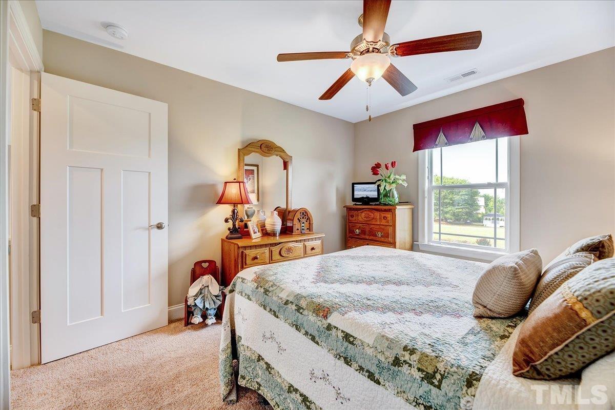 97 Baldwin Ridge Court Willow Spring, NC 27592 - Photo 28 of 46 a bedroom with a bed and a chandelier