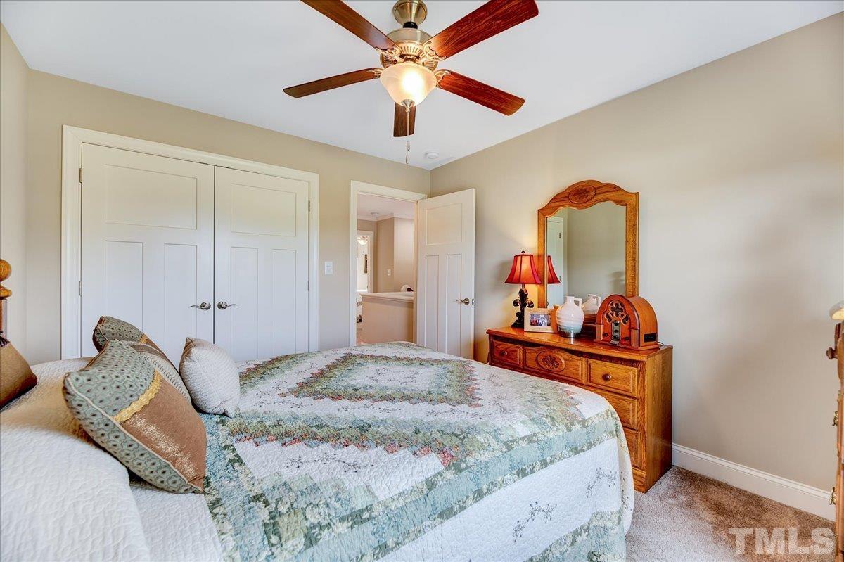 97 Baldwin Ridge Court Willow Spring, NC 27592 - Photo 29 of 46 a bedroom with a bed and a chandelier