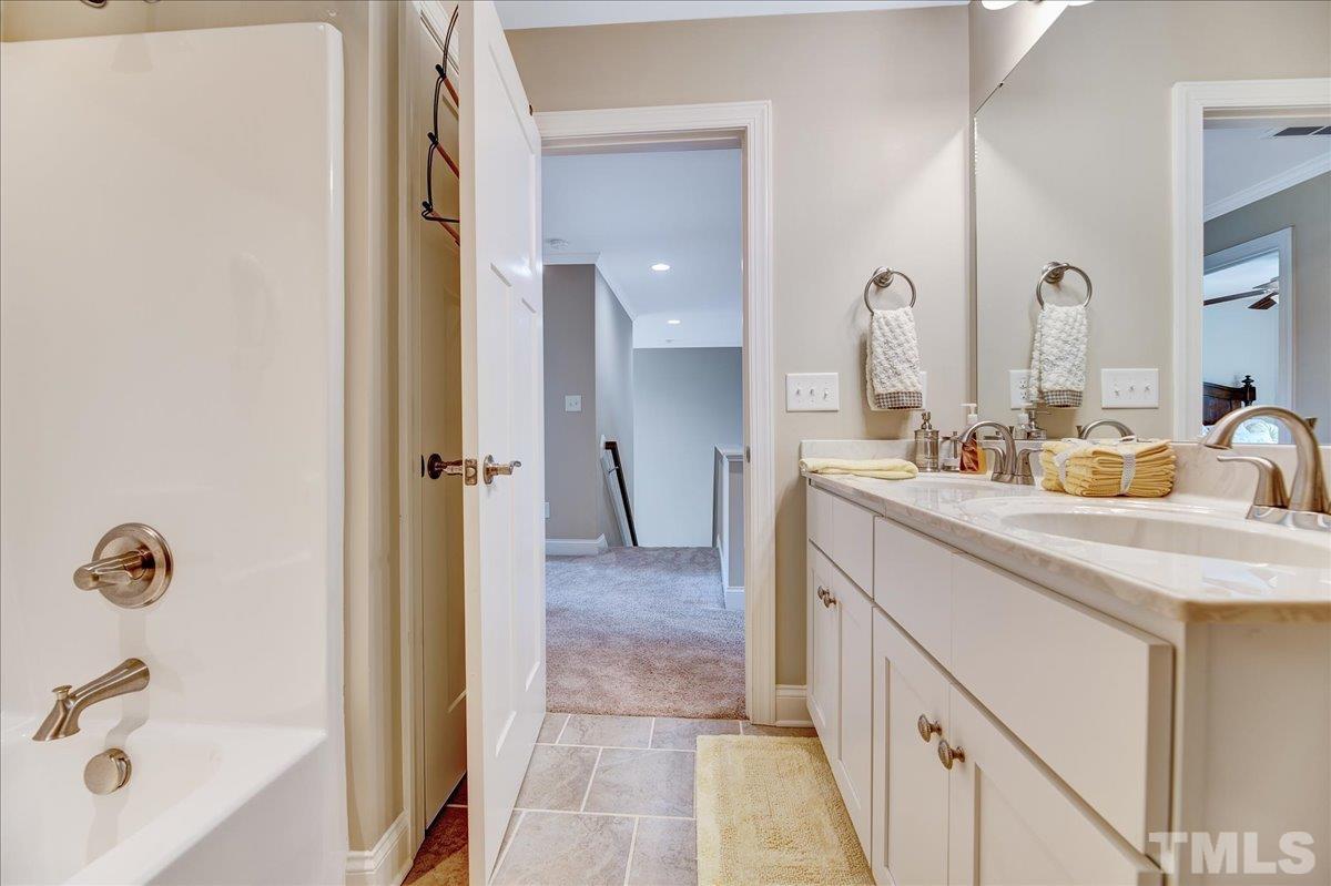 97 Baldwin Ridge Court Willow Spring, NC 27592 - Photo 32 of 46 a bathroom with a double vanity sink a mirror a bathtub and shower