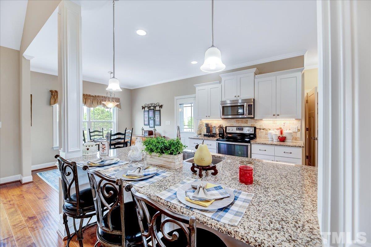 97 Baldwin Ridge Court Willow Spring, NC 27592 - Photo 9 of 46 a open kitchen with stainless steel appliances granite countertop a stove a kitchen island a dining table and chairs with wooden floor