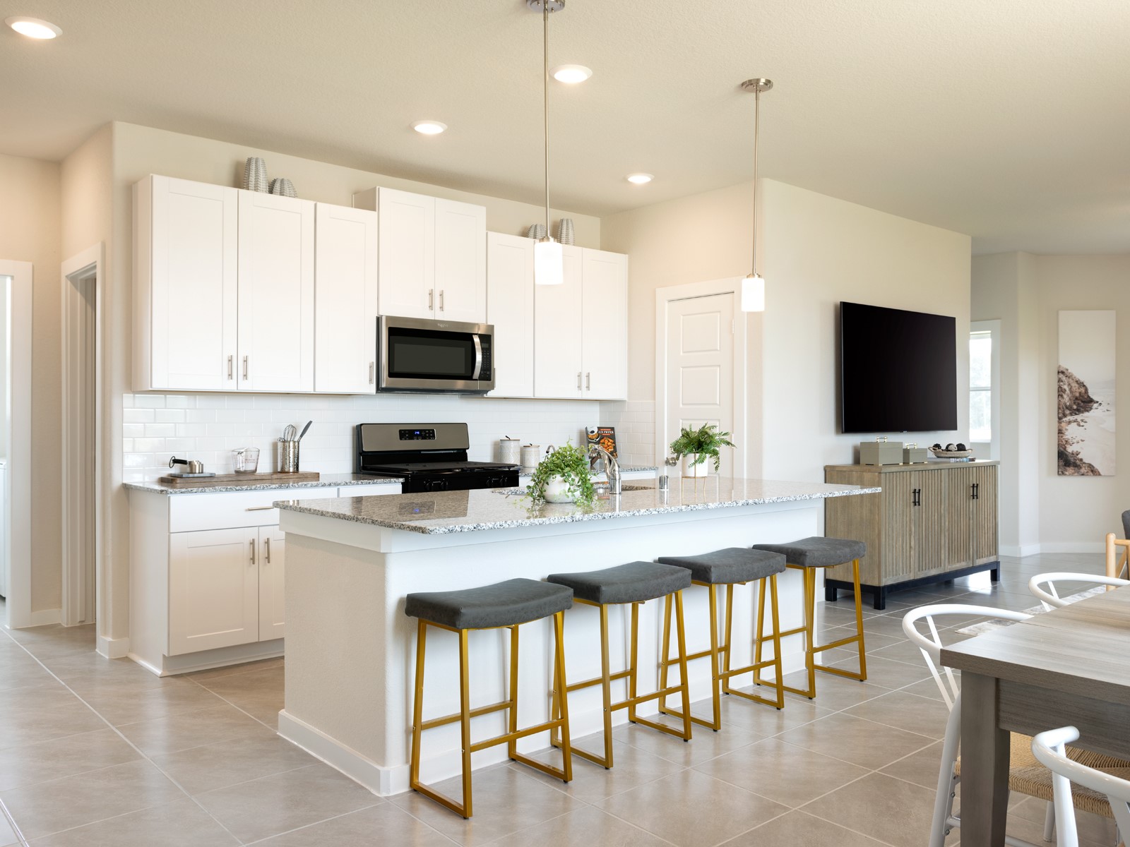 a kitchen with stainless steel appliances a stove a sink a microwave a dining table and chairs