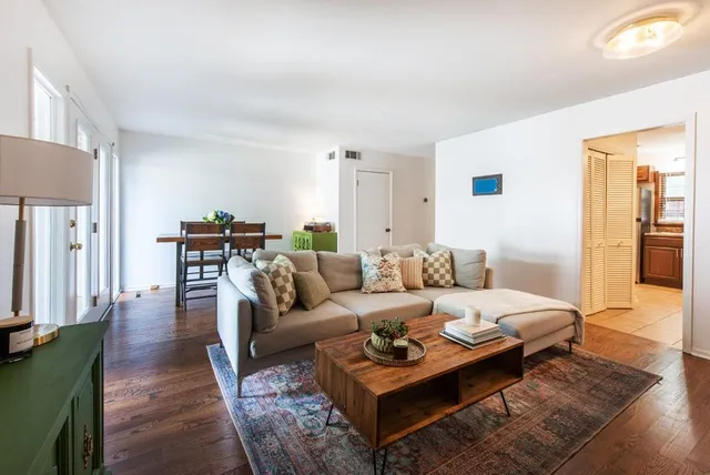 a living room with furniture a lamp and wooden floor
