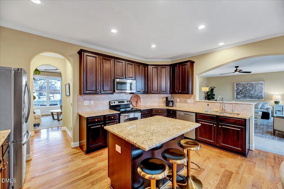 454 Big Willow Way Rolesville, NC 27571 - Photo 8 of 50 a kitchen with a stove a refrigerator and a dining table with wooden floor