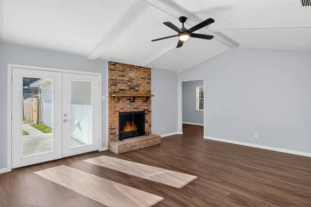 an empty room with wooden floor a ceiling fan and a fireplace