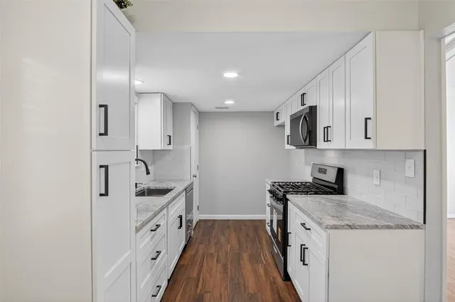 a kitchen with granite countertop white cabinets and stainless steel appliances