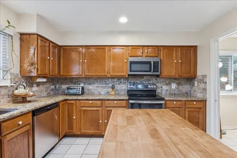 a kitchen with stainless steel appliances granite countertop wooden cabinets a stove top oven a sink and dishwasher