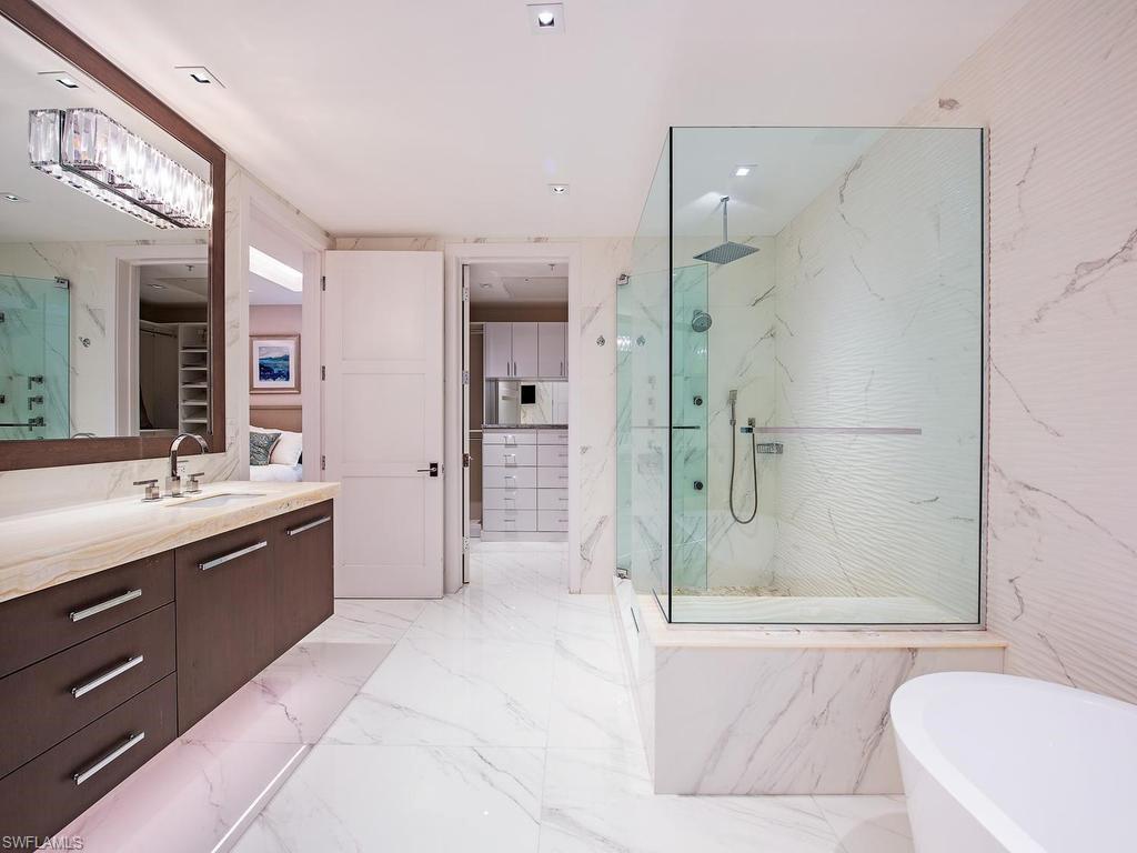 490 5th Street South, Unit 101 Naples, FL 34102 - Photo 14 of 34 a bathroom with a bathtub shower sink and mirror